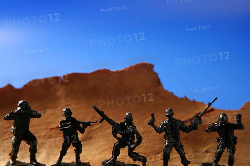 War metaphor, toy little soldiers fighting on wooden mountain