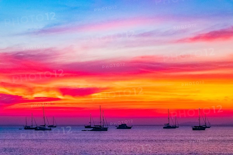 Yachts boats in front of the most beautiful colorful sunset at Tropical Paradise island Koh Phayam Ao Khao Kwai Beach in Ranong Thailand