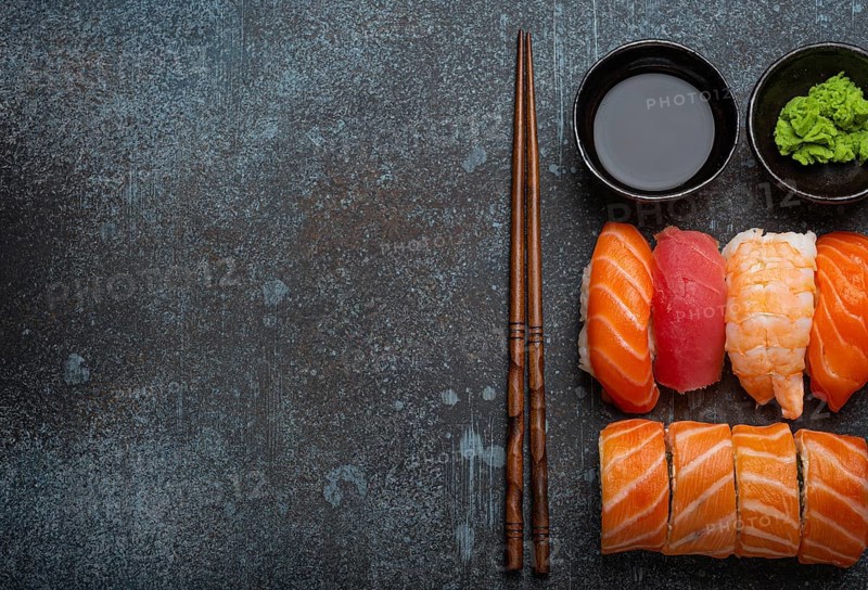 Set of traditional Japanese sushi and rolls top view with soy sauce and chopsticks on rustic stone background. Sushi with salmon, tuna and shrimp, space for text, food photography, food photography