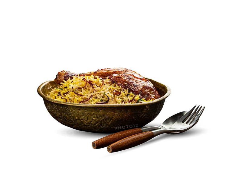 Delicious Indian dish Biryani chicken leg with basmati rice in metal brass old bowl with fork and spoon, isolated on white background. Traditional non-vegetarian food of India, food photography, food photography