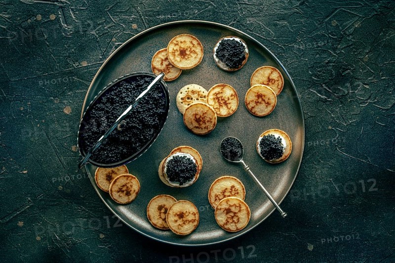 Blinis with black caviar and cream cheese, overhead flat lay shot on a black background, mini pancakes, an elegant appetizer, Food photography, Food photography