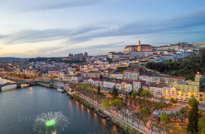 Coimbra drone aerial city view at sunset with colorful fountain in Mondego river and beautiful historic buildings, in Portugal