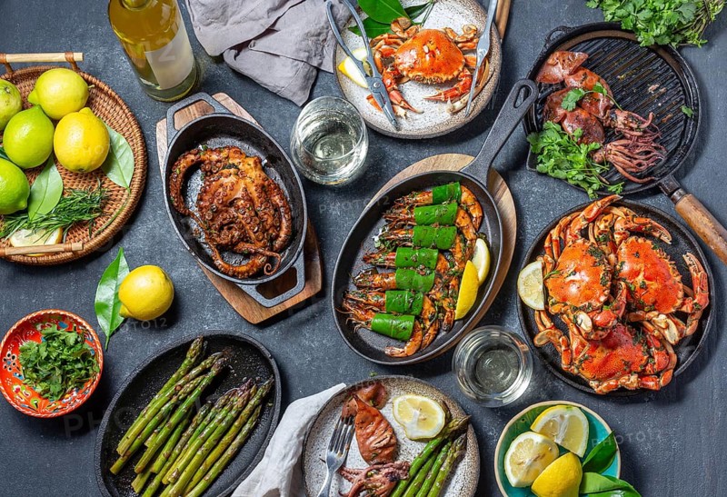 Food, Food, Set table with seafood dishes, cooked crabs, tiger shrimps, grilled octopus and squids on cast iron grilled pans and plates, White wine. Top view