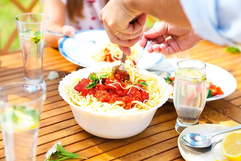 Family dinner variety of Italian dishes on wooden table in the garden