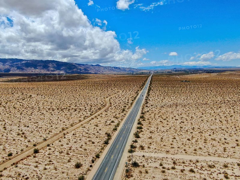 Aerial view of endless desert straight dusty asphalt road in Joshua Tree Park. USA. Long straight tarmac road heading into the desert to the direction of Arizona