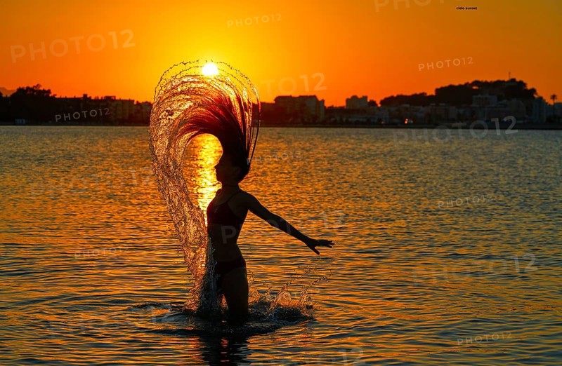 Girl flipping hair flip at sunset beach in orange sky