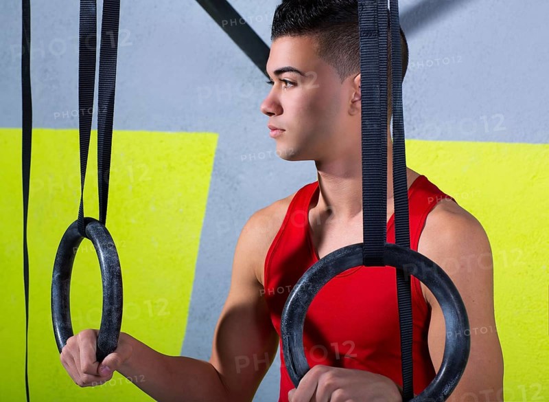 Crossfit dip ring young man relaxed after workout at gym dipping exercise