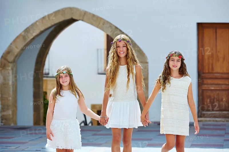 Kid girls walking hand in hand at white Mediterranean village of Spain