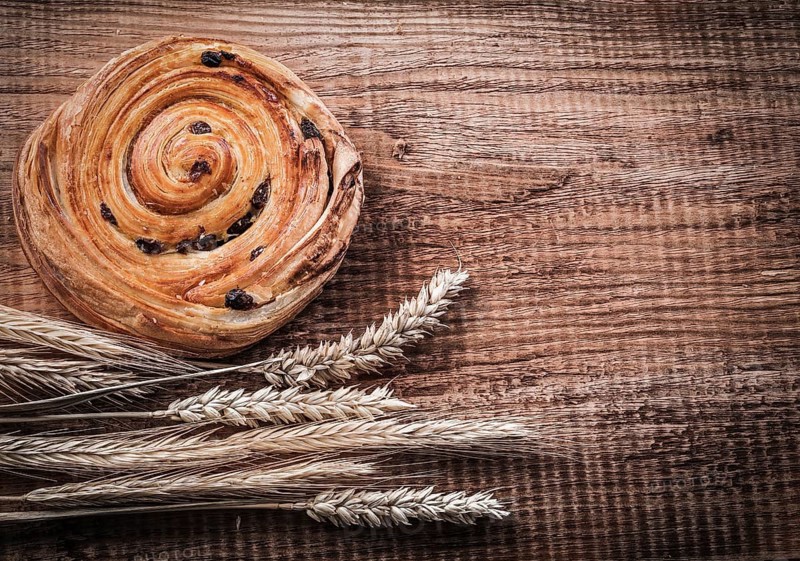 Rich raisin bakery bunch of wheat ears on oak wooden board food and drink concept