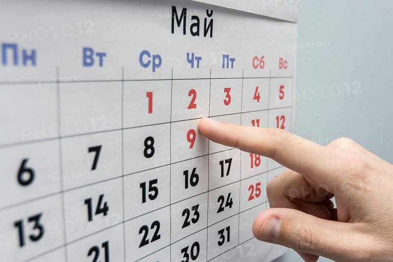 Hand points to the May 2 holiday on a wall calendar sheet