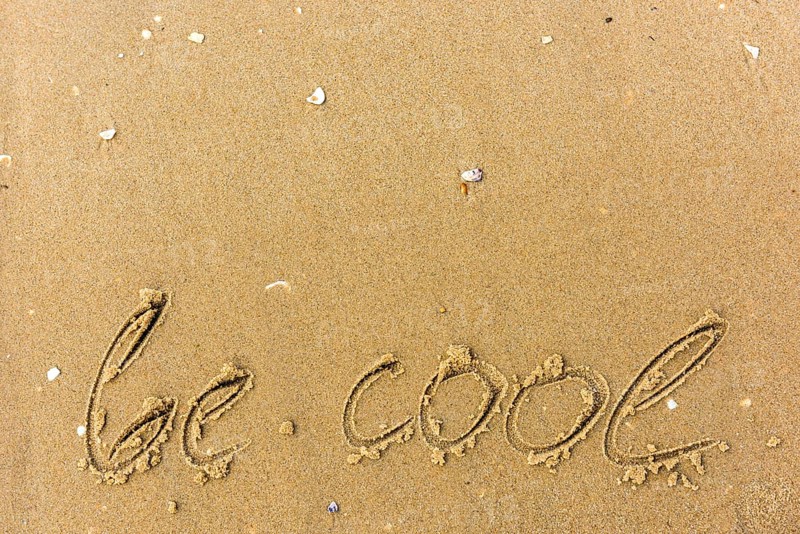 Be cool written on the beach. sand background