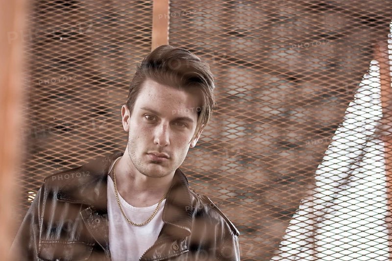 Handsome young man standing outdoors in urban environment on metal stairs