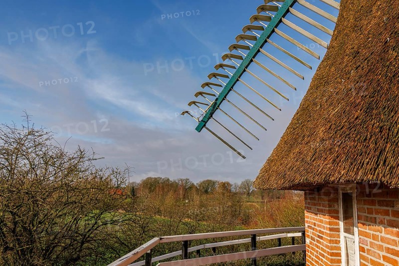 Windmill wing shot with surrounding nature, thatched roof and bright sky, burlage, east frisia, germany