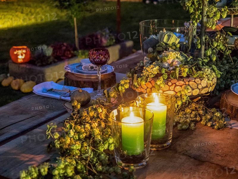 Two green candles glowing on a decorated outdoor table, surrounded by flowers and other decorative elements in an evening atmosphere, borken, münsterland, Germany, Europe