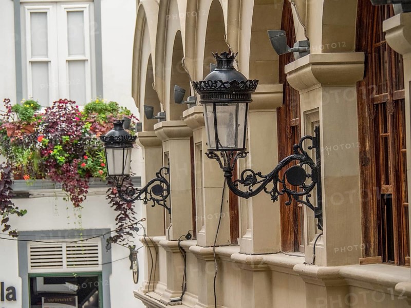 Historic lanterns hanging on the wall of a building with arches and plants in the city, la palma, canary islands, spain