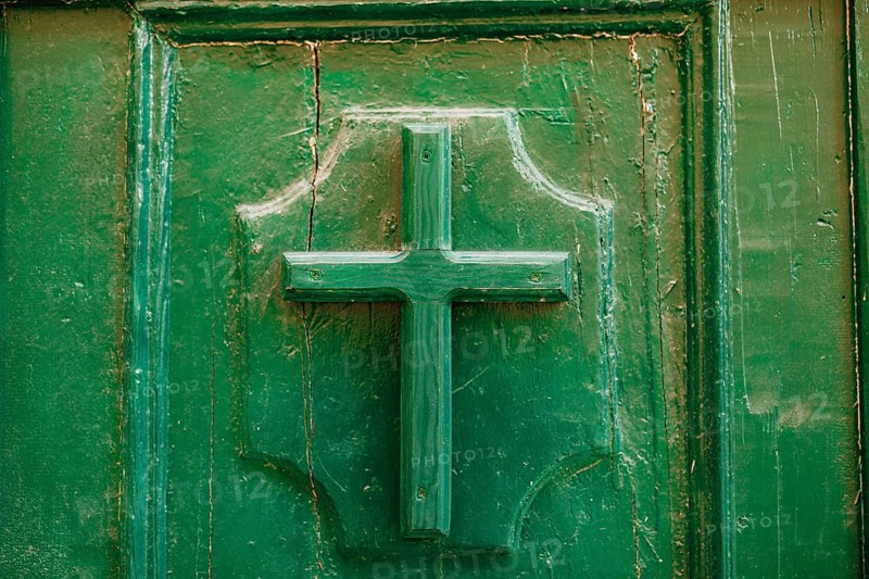 The entrance to the church. Cross on a wooden door green