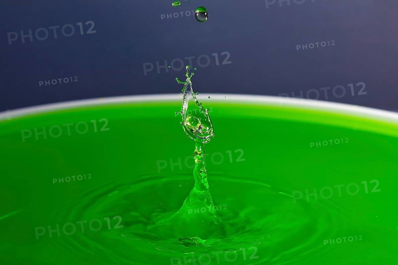 A drop of water forms a splashing sculpture on green liquid, water droplets, collision, high-speed photography, concept, water figures