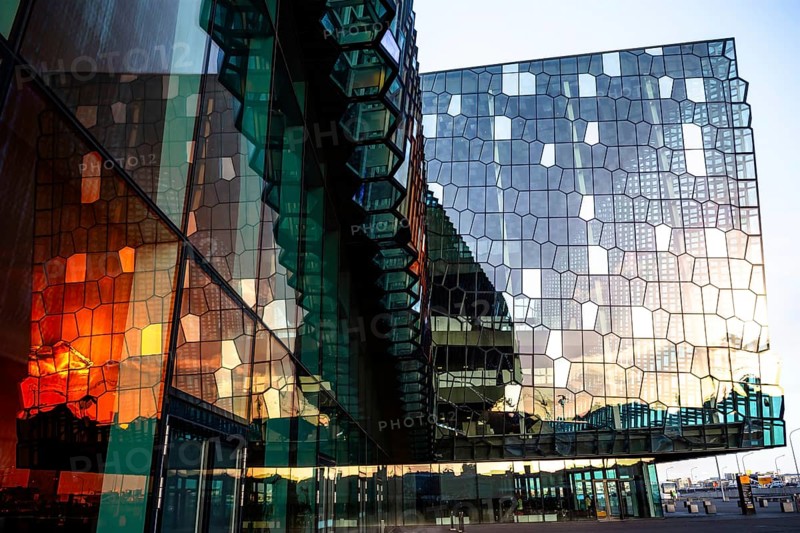 A modern building with a reflective glass façade, reflecting the setting sun, Harpa Concert Hall, Reykjavik, Iceland, Europe