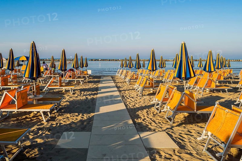 Rows of orange umbrellas and deckchairs on the beach of Igea Marina near Rimini