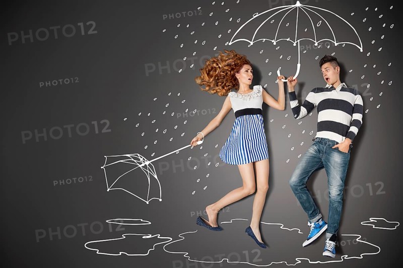 Happy valentines love story concept of a romantic couple in the rain against chalk drawings background