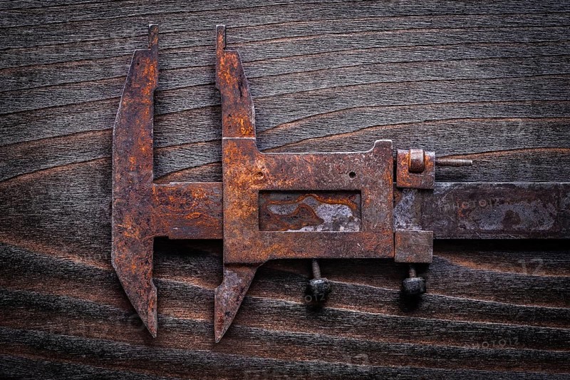 Rusted old-fashioned measuring slide caliper on vintage wooden board construction concept