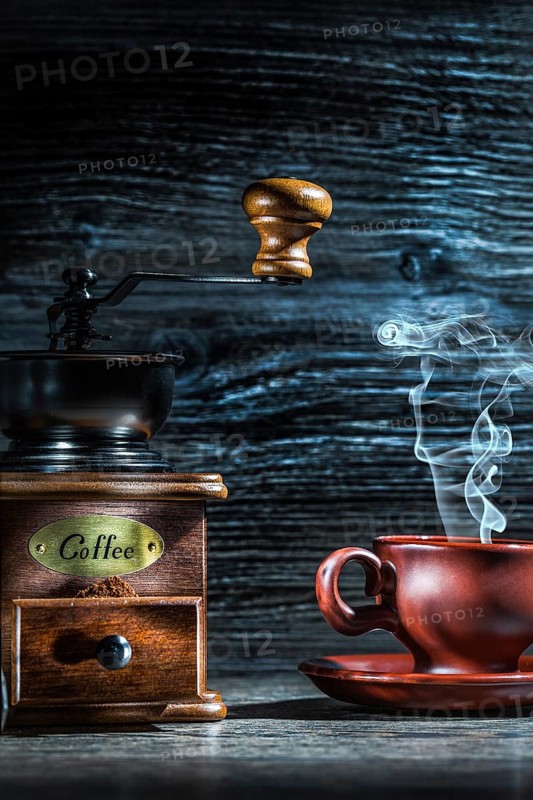 Steamy coffee cup and mill on vintage wood