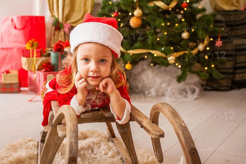 Little child in christmas hat dreaming about christmas miracle. Girl makes a wish an new year night