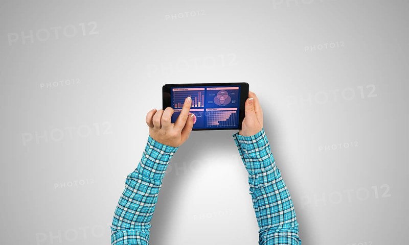 Top view of girl hands using tablet pc with diagrams and graphs on screen
