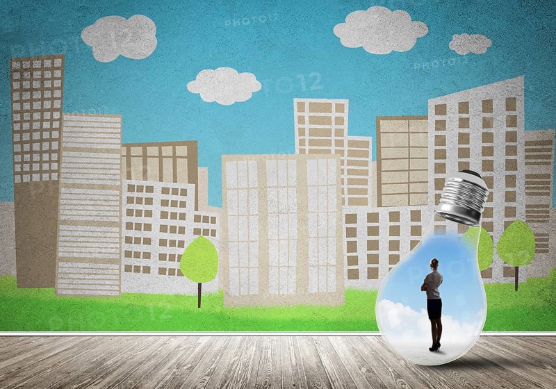Businesswoman inside light bulb against city drawn concept