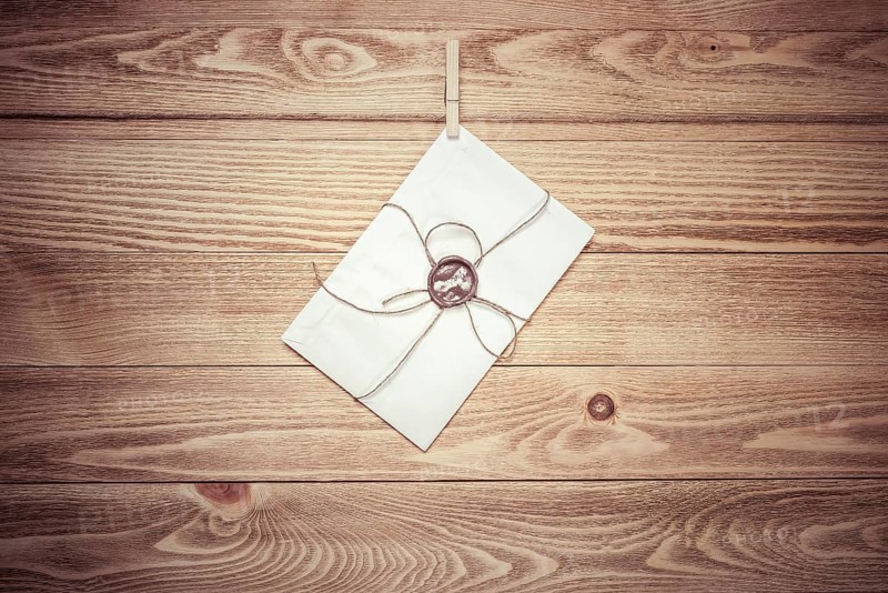Envelope hanging on rope on wooden background