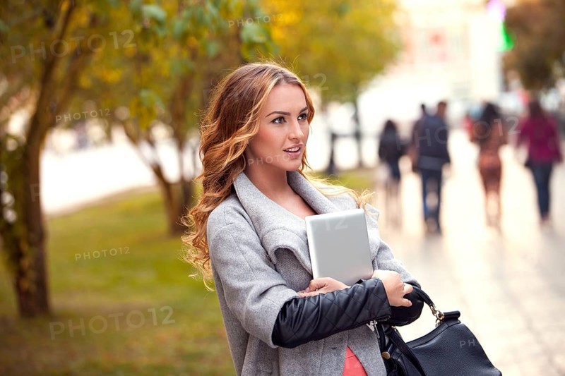 A businesswoman with a tablet walking in a city park