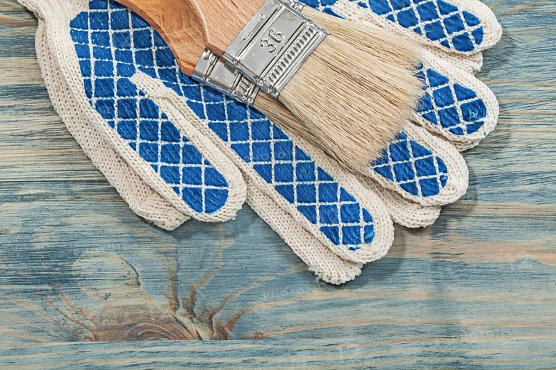 Paintbrushes protective gloves on wooden board construction concept