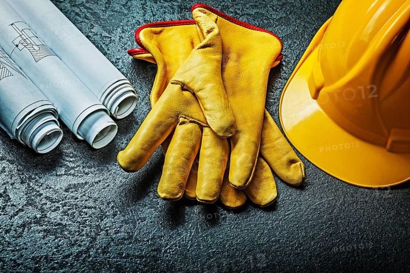 Working gloves with yellow helmet and rolled blueprints