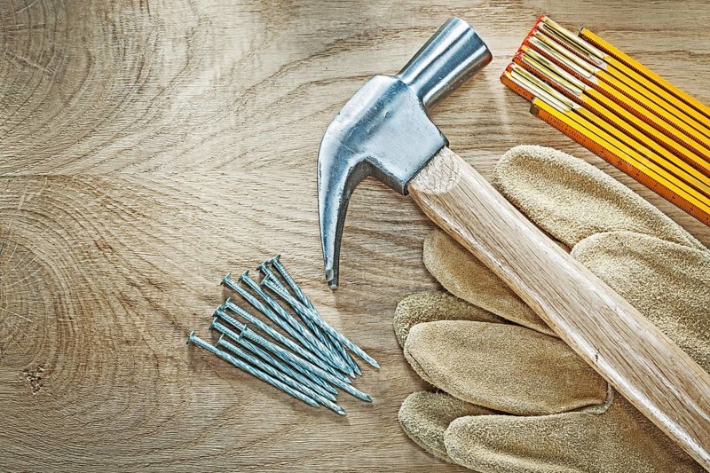 Set of protective gloves wooden meter claw hammer nails on wood board construction concept