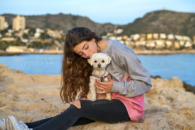 Girl playing with maltichon puppy dog in the beach