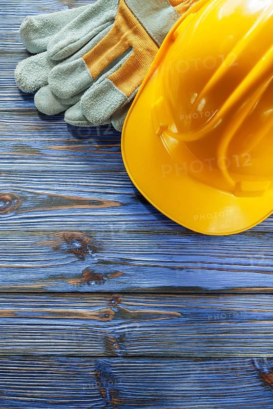 Protective gloves hard hat on vintage wooden board