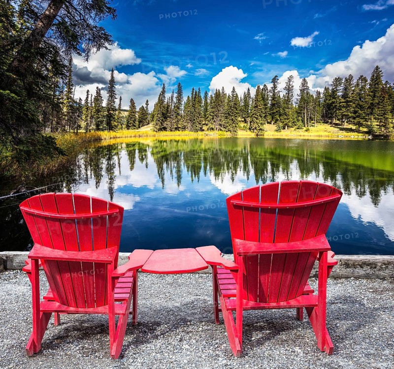 Jasper National Park in the Rocky Mountains. Two red plastic chairs on the lake. On shores of the lake grow coniferous forests