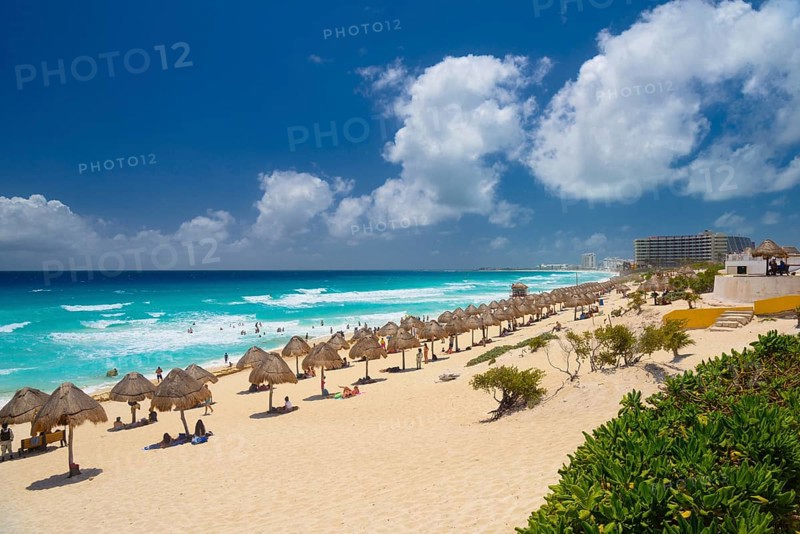 Umbrellas on a sandy beach with azure blue water on a sunny day near Cancun, Mexico, Central America
