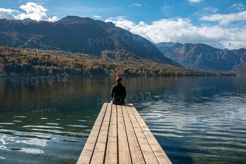 Sitting on a small jetty and enjoying the view on the landscape of lake Bohinj in the Triglav National Park, The Julian Alps, Slovenia, Europe