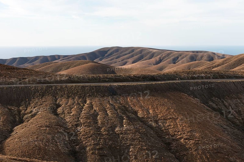 Gentle brown hills under a blue sky in an arid landscape. Viewpoint Mirador Astronomico de Sicasumbre around Pajara, Fuerteventura, Canary Islands, Spain, Europe