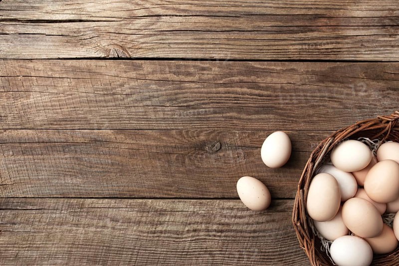 Organic chicken eggs in basket on wooden background. Organic household concept with eggs from free-range and pasture raised hens
