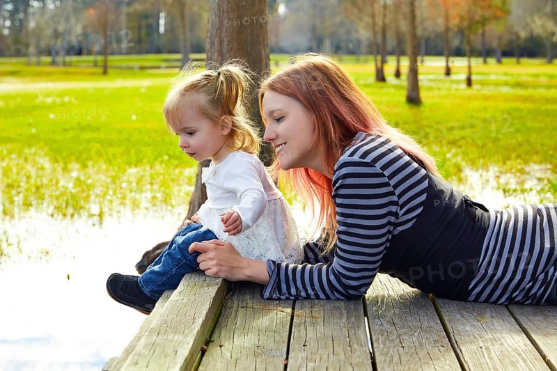 Daughter and mother playing together in the park lake pier