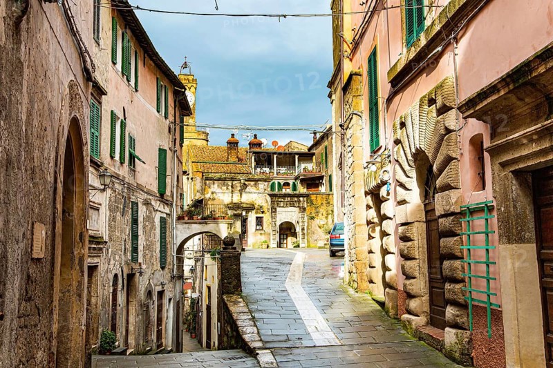 Narrow streets of the picturesque tuff town of Sorano. Etruscan towns of Tuscany. Fairy-tale stone fortress on top of a wooded hill. Towns that have existed for the second millennium. The tuff city of Sorano. Tuscany, Italy. A small town from the Etruscan triangle - the ancient part of the Tuscan hills. The fortress of Sorano