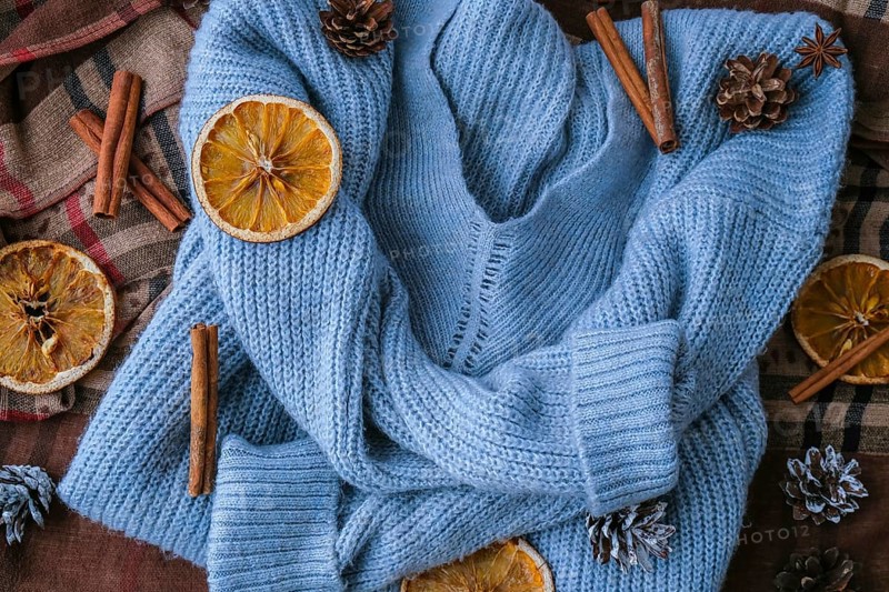 Blue sweater and cinnamon sticks and anise star. Dry slices of citrus orange and cones. Hot winter cocktail. Christmas, Thanksgiving drinks. Autumn, grog, hot sangria, mulled wine. Festive holiday flat lay atmosphere