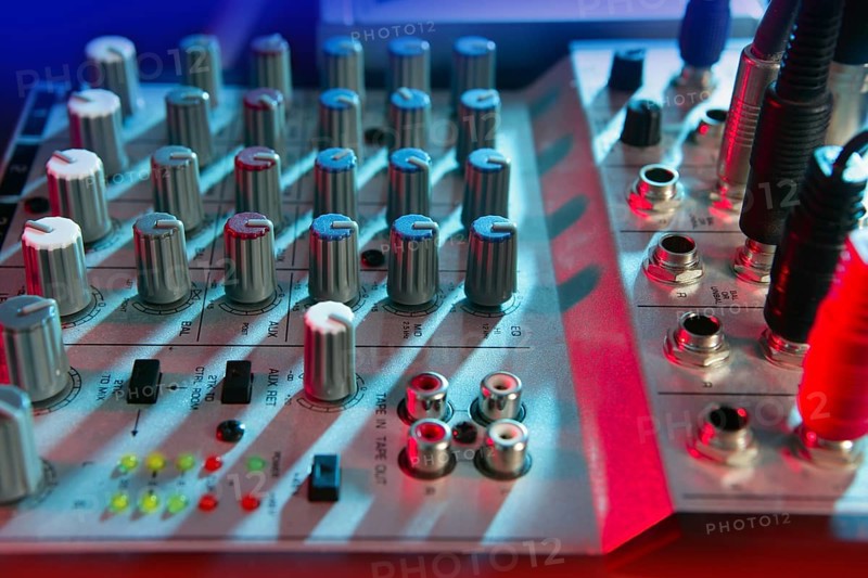 Audio mixer music desk under colorful lights equipment