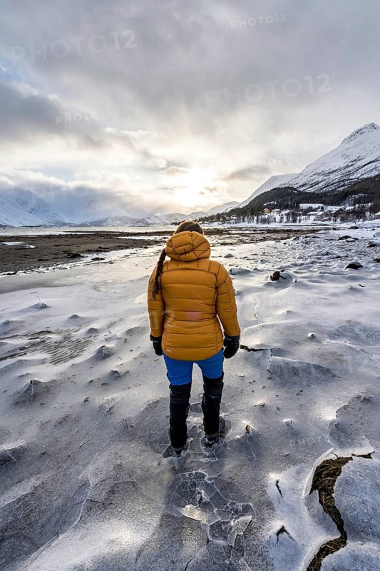 A woman in winter clothing on the frozen shore of the Ullsfjord, Sjursnes, Tromso, Troms, Norway, Europe