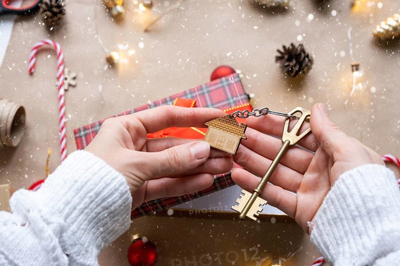 Key to house with keychain on cozy home in gift box with Christmas decor packaging. Pack present for New Year, Christmas. Building, project, moving to new house, mortgage, rent, purchase real estate