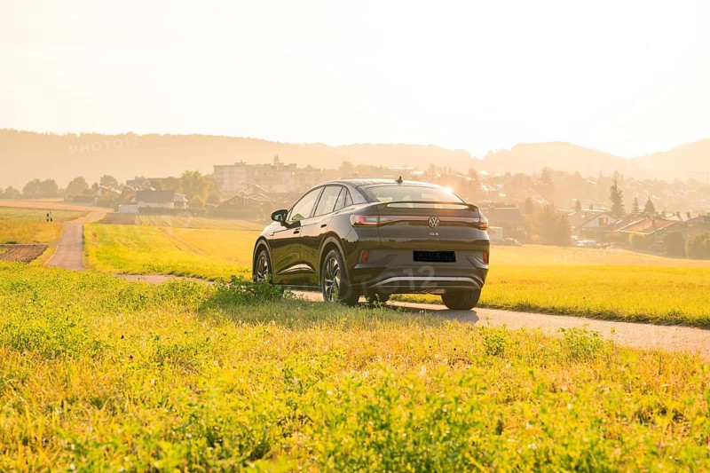 SUV driving on a country road with a view of a town at sunset, VW ID5 electric car, Calw, Black Forest, Germany
