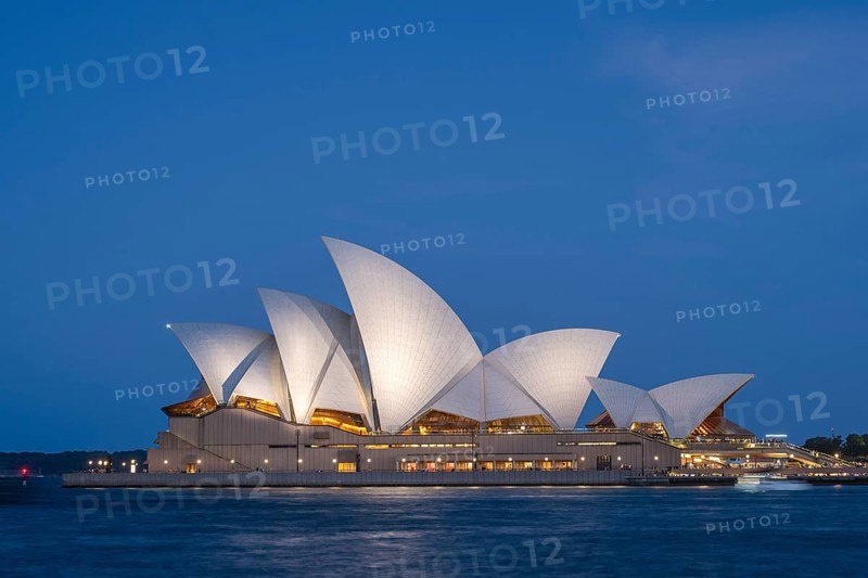 Illuminated Sydney Opera House at night train blue hour, surrounded by water, with unique architecture and vibrant atmosphere, Sydney, Australia