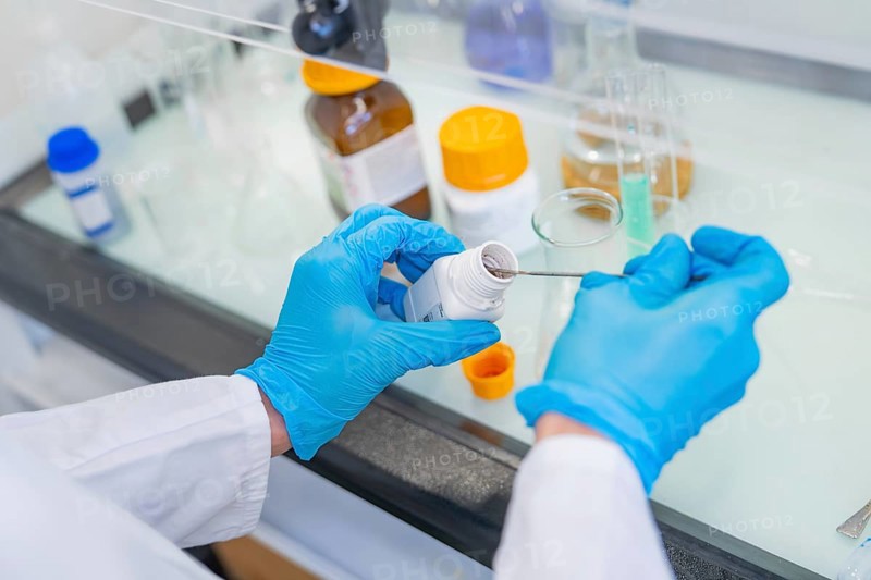 Person in a laboratory puts a small amount of powder into a beaker with a spatula, Youth Research Centre Nagold, Black Forest North, district of Calw, Germany